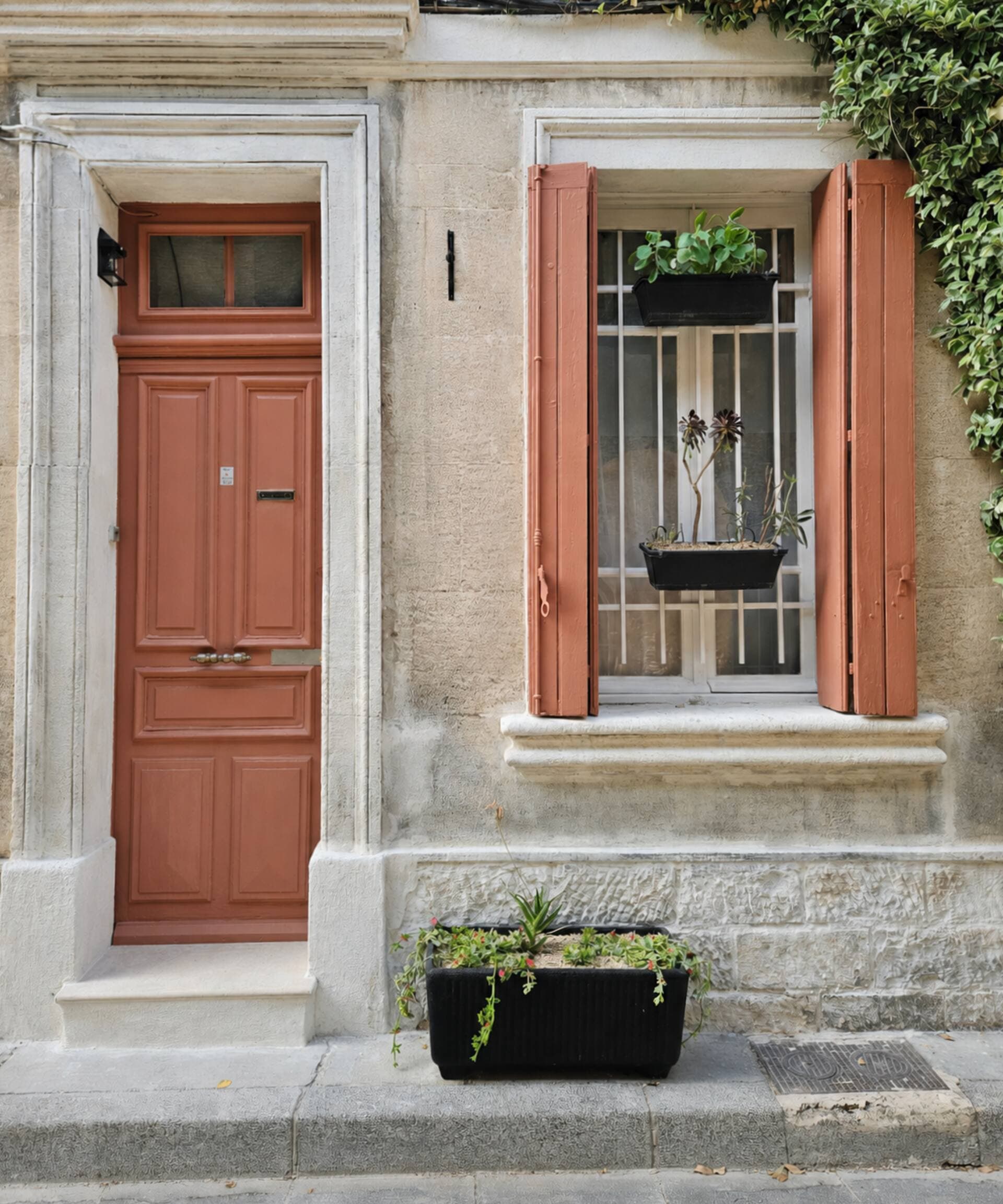 La façade en pierre de la maison, porte et volets terre cuite, dans une rue d'Avignon